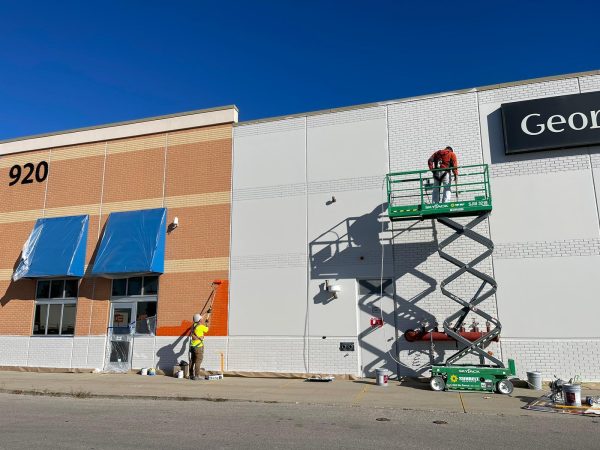 Commercial exterior painting on a retail building using a scissor lift